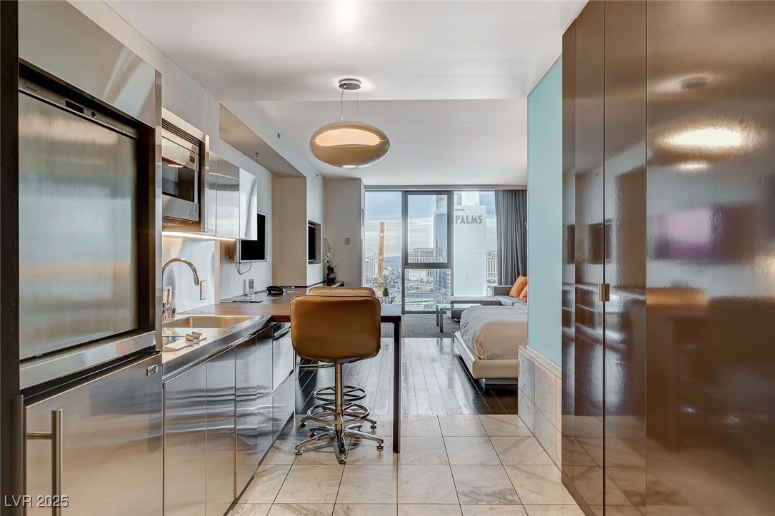 4381 West Flamingo Road, Unit 2204 Las Vegas, NV 89103 - Photo 27 of 27 Kitchen with appliances with stainless steel finishes, floor to ceiling windows, hanging light fixtures, open floor plan, and modern cabinets
