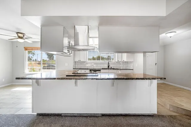 a kitchen with stainless steel appliances granite countertop a sink a stove and a wooden floors
