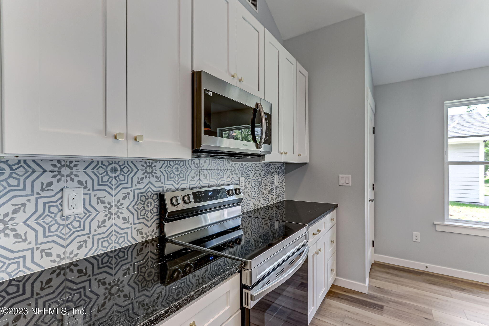 45115 South Mickler Street Callahan, FL 32011 - Photo 13 of 24 a kitchen with stainless steel appliances granite countertop a stove a microwave and a white cabinets