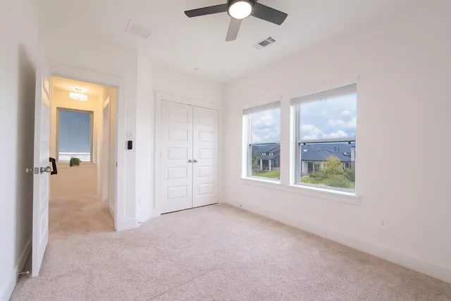 an empty room with chandelier fan and windows