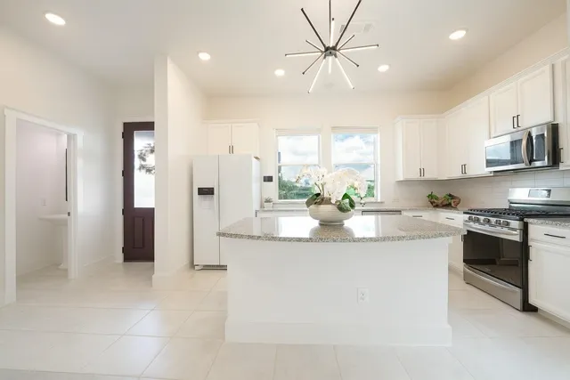 a kitchen with stainless steel appliances granite countertop a sink and a refrigerator