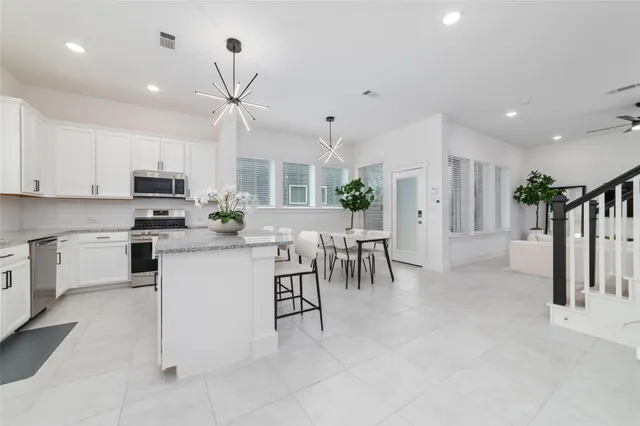 a kitchen with stainless steel appliances kitchen island granite countertop a stove top oven a sink a dining table and chairs