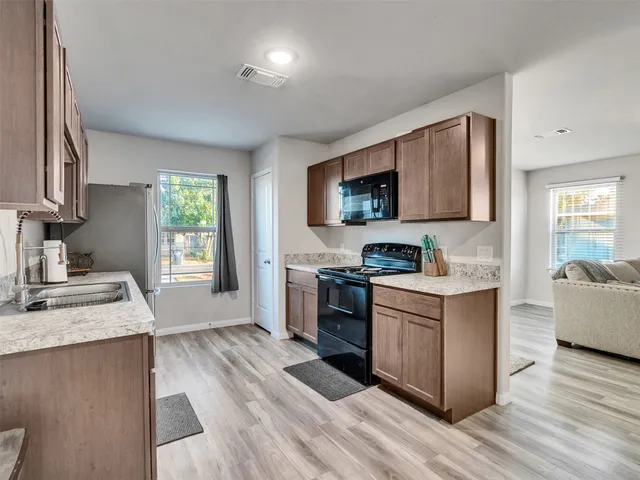a kitchen with granite countertop a sink wooden floor and stainless steel appliances