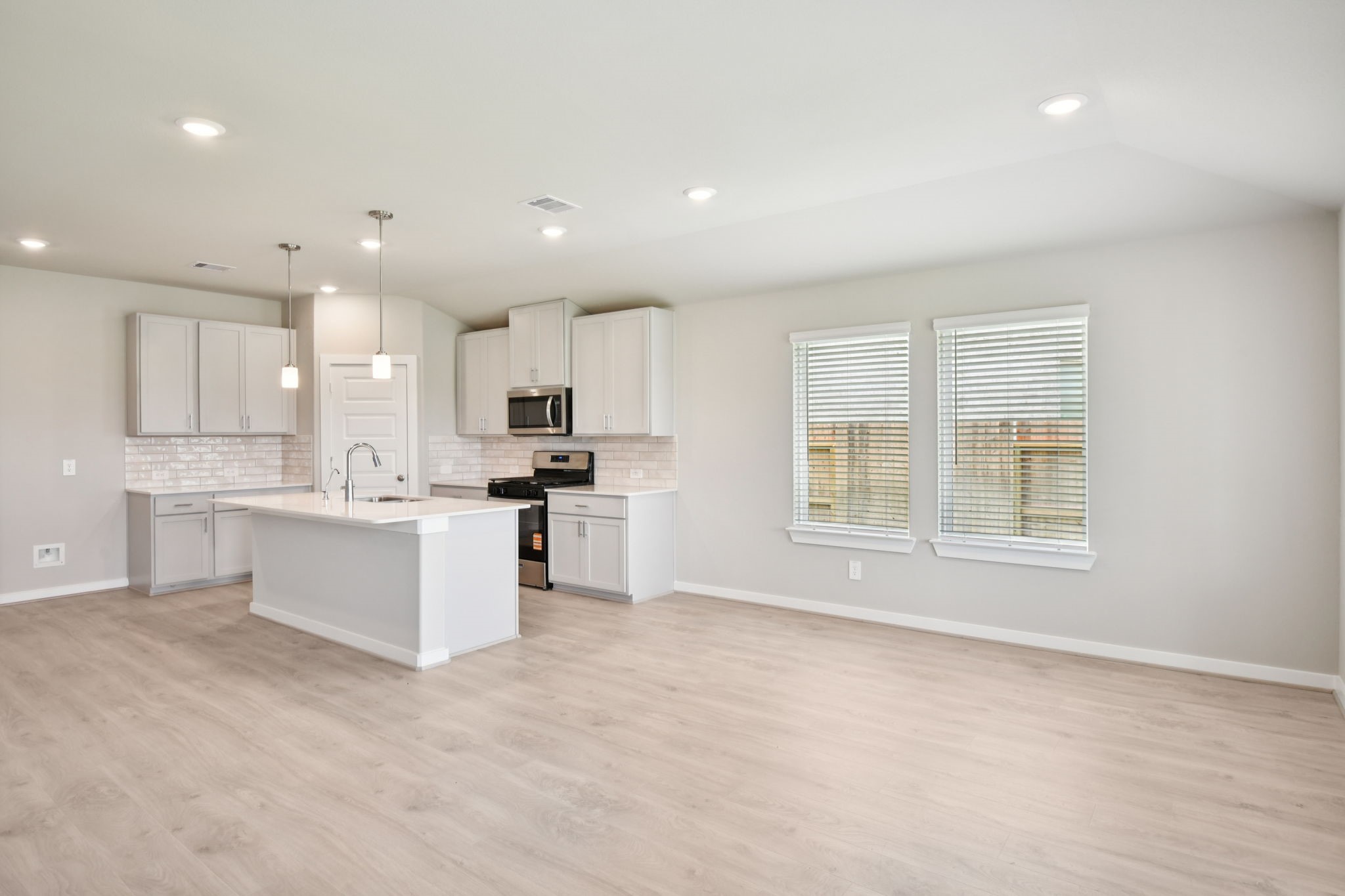 5814 Chamberlain Crossing Rosenberg, TX 77471 - Photo 8 of 39 a large white kitchen with kitchen island a sink a stove a refrigerator and white cabinets