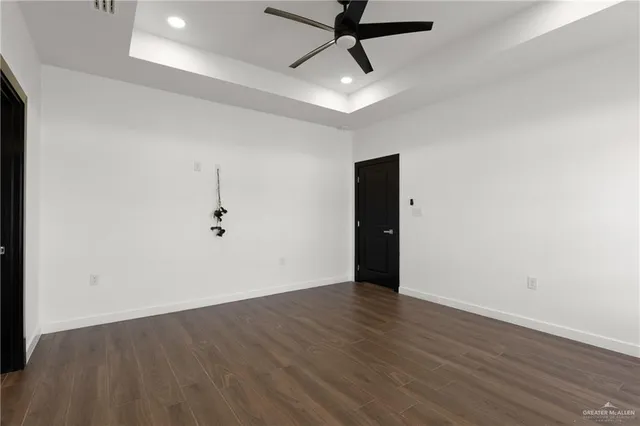 an empty room with wooden floor and ceiling fan