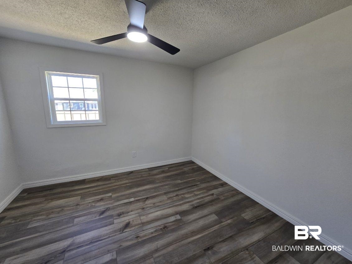 821 Dailey Street Brewton, AL 36426 - Photo 14 of 17 Spare room with dark wood finished floors, ceiling fan, and a textured ceiling