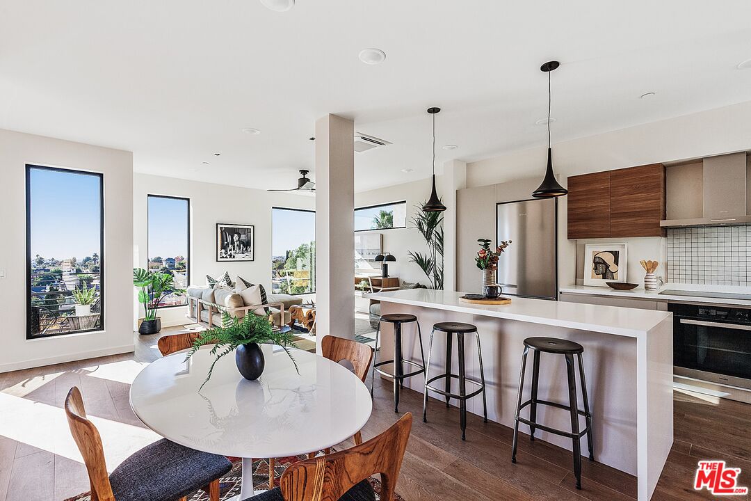 a kitchen with stainless steel appliances a dining table chairs and white cabinets
