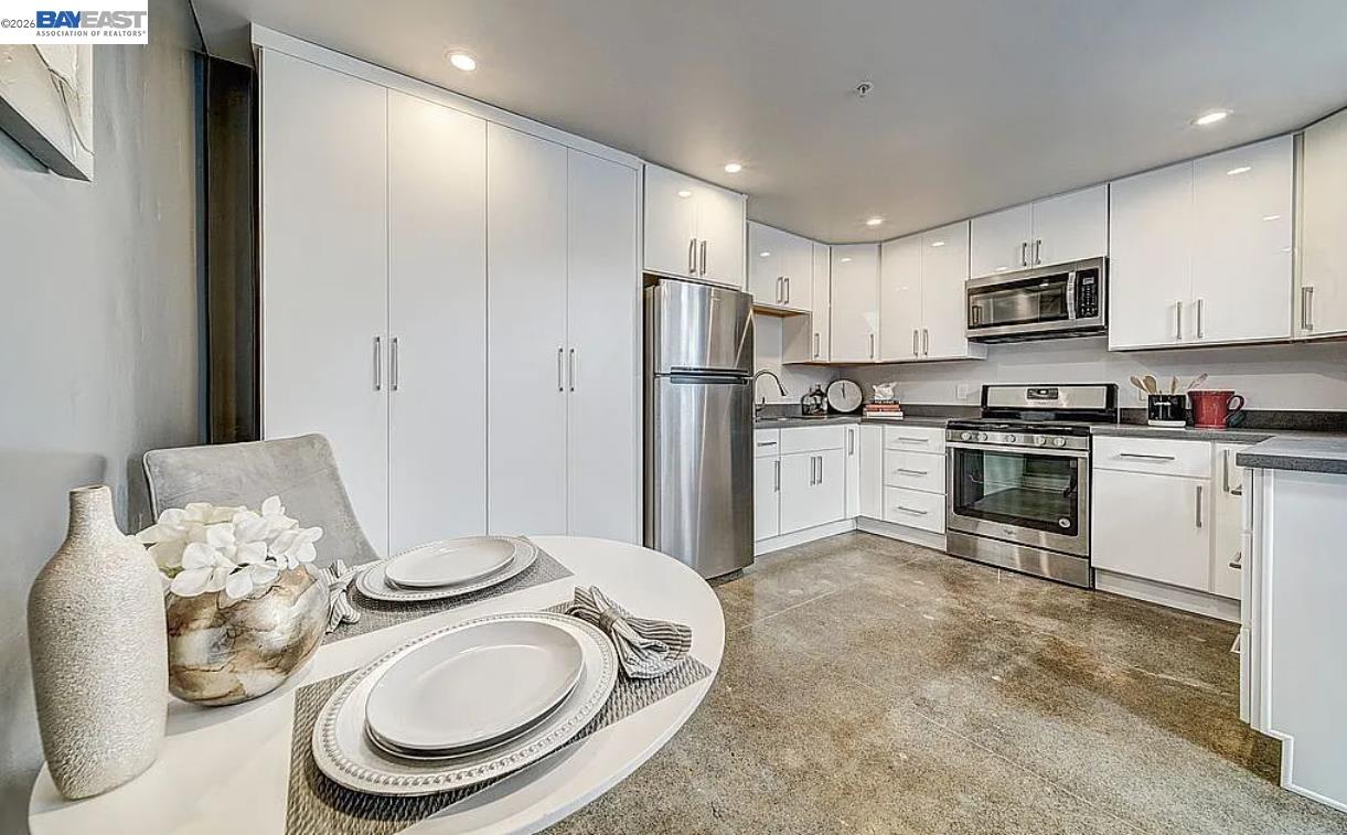 1451 13th Street, Unit 1 Oakland, CA 94607 - Photo 4 of 10 a kitchen with stainless steel appliances granite countertop a refrigerator a stove a sink and white cabinets with wooden floor