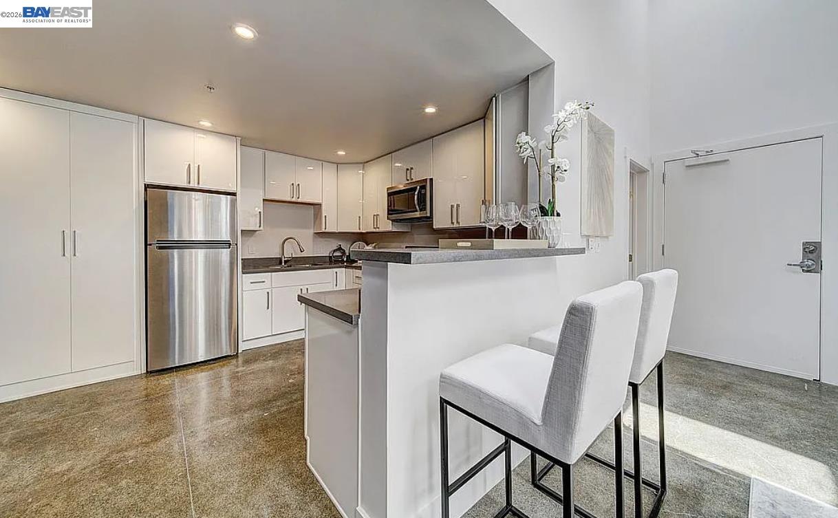 1451 13th Street, Unit 1 Oakland, CA 94607 - Photo 5 of 10 a kitchen with kitchen island a refrigerator stove and microwave