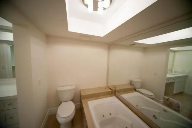 a bathroom with a granite countertop toilet sink and mirror