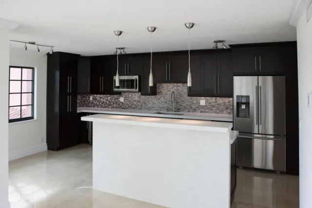 a kitchen with stainless steel appliances granite countertop a refrigerator and a sink
