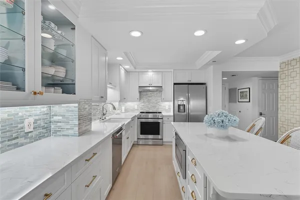 a large kitchen with a large counter top a sink stainless steel appliances and cabinets