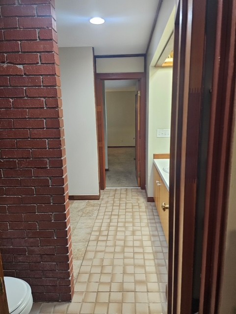 114 Houston Street Clemson, SC 29631 - Photo 11 of 19 An exposed brick feature wall defines the transition between tiled hallways and adjoining rooms.