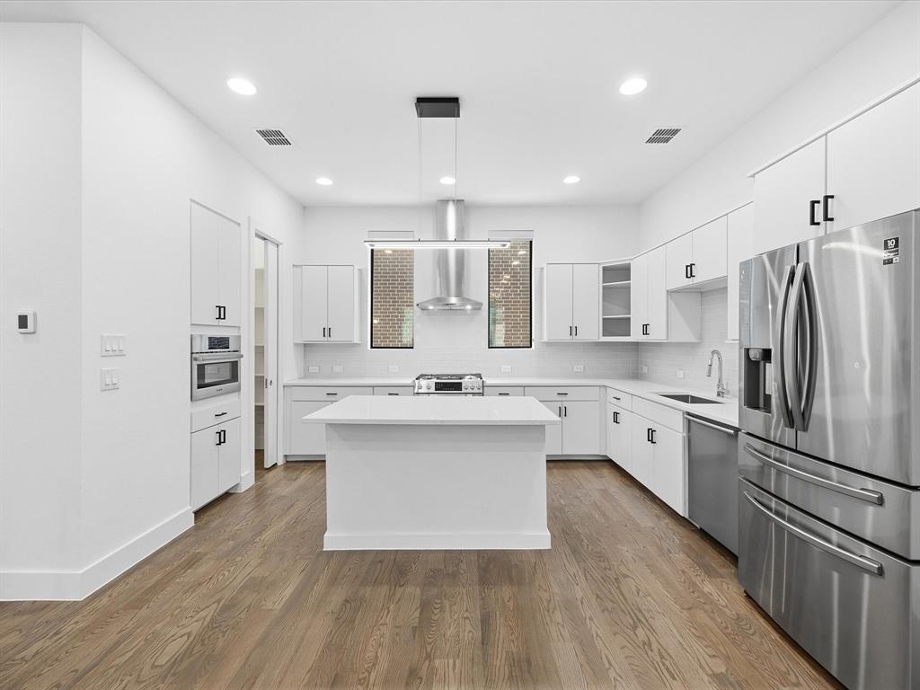 1920 Dowgate Court Dallas, TX 75204 - Photo 14 of 38 Kitchen with glass insert cabinets, stainless steel appliances, white cabinetry, and decorative light fixtures