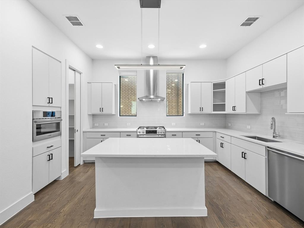 1920 Dowgate Court Dallas, TX 75204 - Photo 15 of 38 Kitchen with stainless steel appliances, white cabinets, dark wood-style floors, and a center island