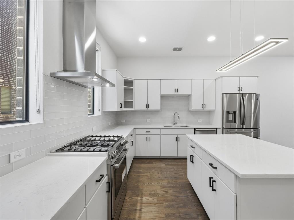 1920 Dowgate Court Dallas, TX 75204 - Photo 18 of 38 Kitchen with stainless steel appliances, range hood, dark wood-type flooring, white cabinets, and light stone counters