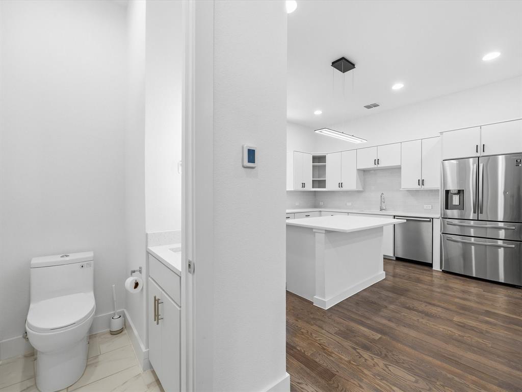 1920 Dowgate Court Dallas, TX 75204 - Photo 19 of 38 Kitchen with white cabinets, stainless steel appliances, glass insert cabinets, hanging light fixtures, and tasteful backsplash