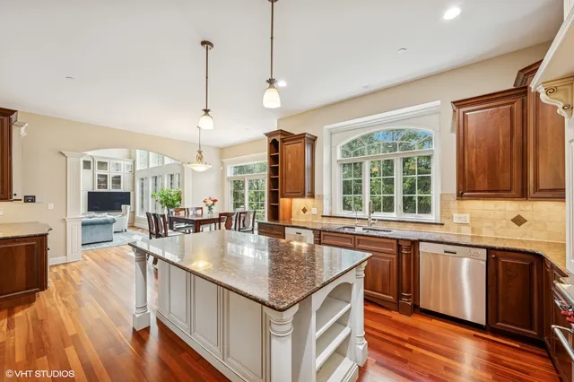 a open kitchen with stainless steel appliances granite countertop a stove and a large countertops with wooden floor