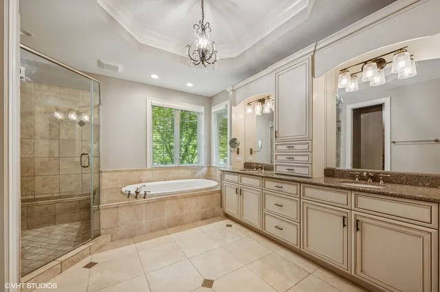 a spacious bathroom with a granite countertop tub sink a mirror a shower and vanity