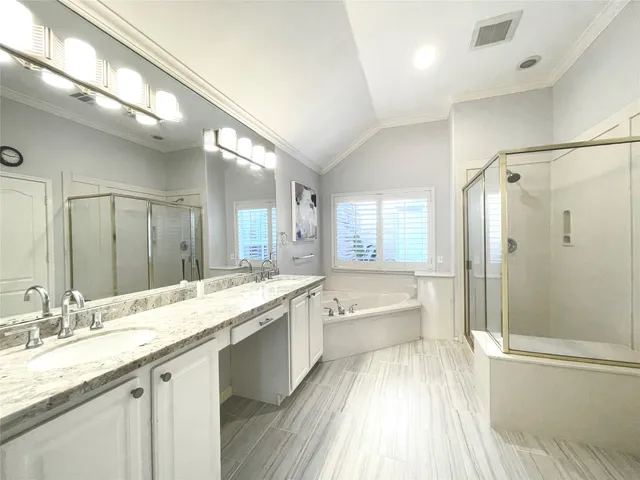 a bathroom with a granite countertop double vanity sink a mirror and a bathtub