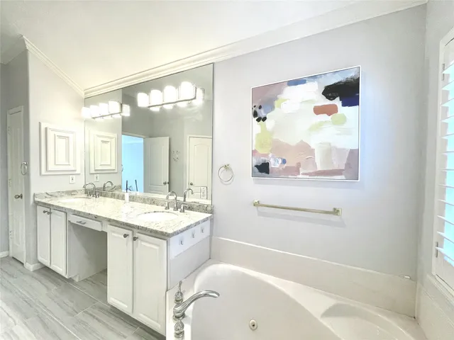 a bathroom with a granite countertop sink mirror bathtub and next to a window