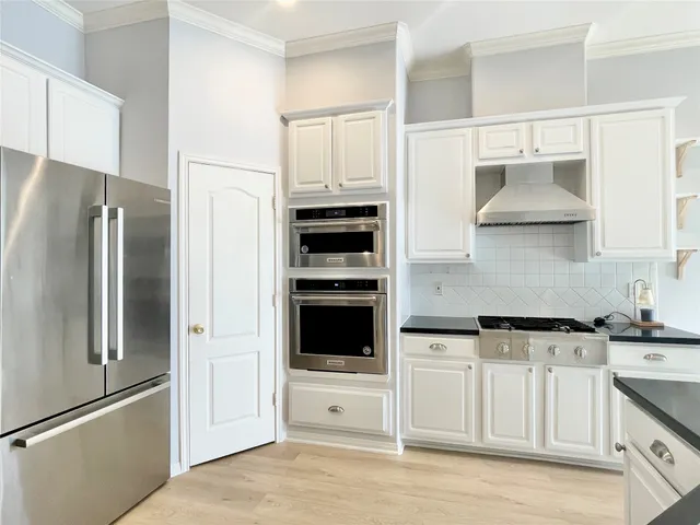 a kitchen with stainless steel appliances white cabinets and a refrigerator