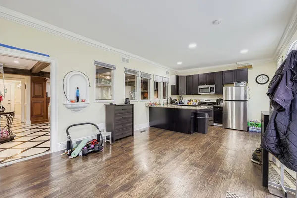 a kitchen with stainless steel appliances a refrigerator a sink a stove and white cabinets with wooden floor