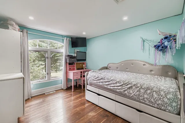 a bedroom with a bed and a flat tv screen on dresser