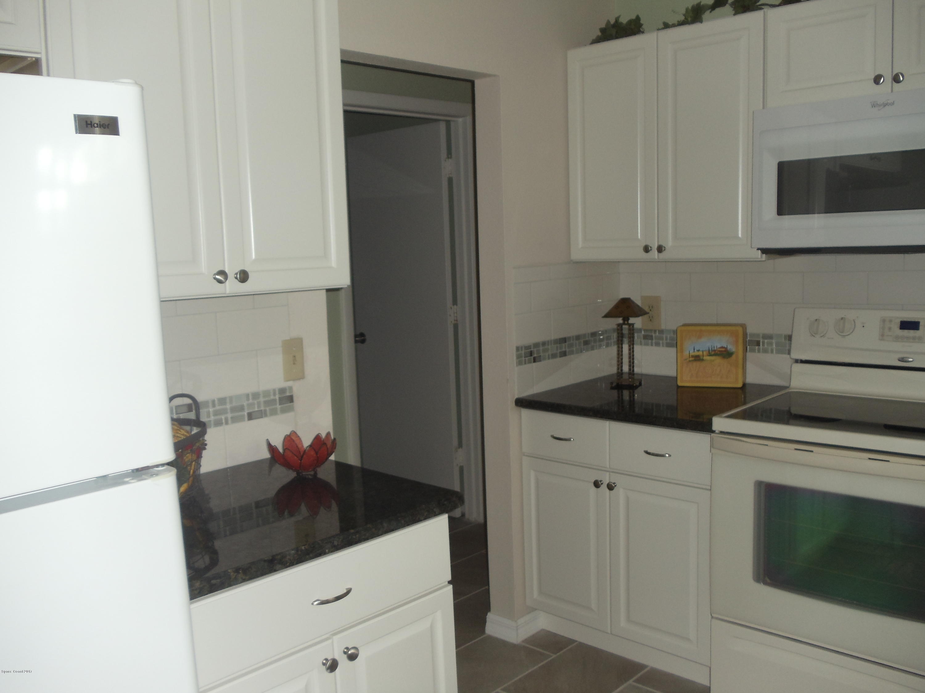 271 Trilby Road Southwest Palm Bay, FL 32908 - Photo 15 of 27 a kitchen with white cabinets and white appliances