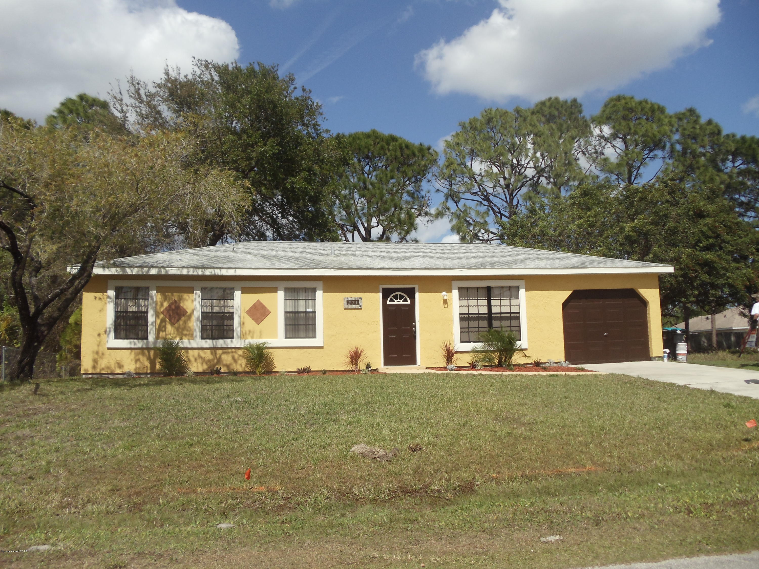 271 Trilby Road Southwest Palm Bay, FL 32908 - Photo 3 of 27 a front view of house with yard and trees in the background