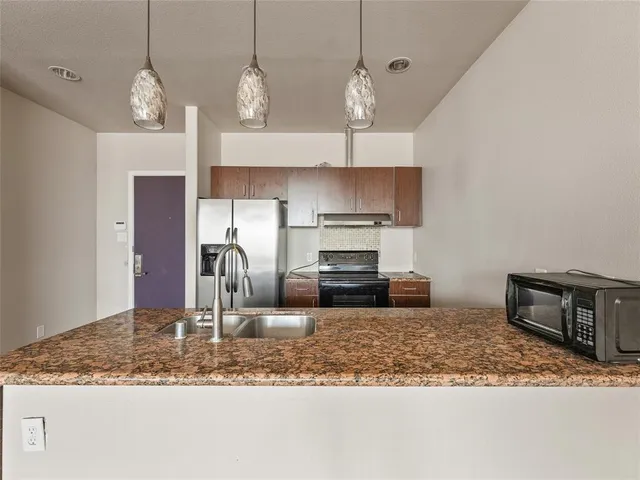 a kitchen with stainless steel appliances granite countertop a sink a stove and a microwave
