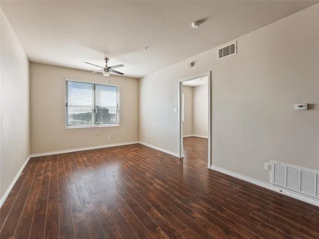 an empty room with wooden floor chandelier and windows