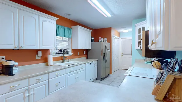 a kitchen with stainless steel appliances granite countertop a refrigerator a sink dishwasher a oven with white cabinets and wooden floor