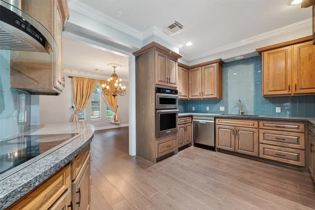 a kitchen with granite countertop a sink cabinets stainless steel appliances and a counter top space