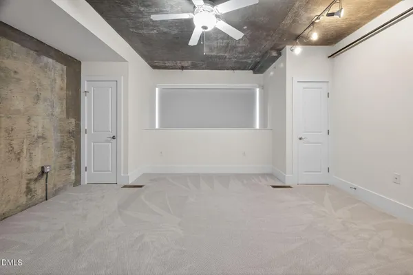 an empty room with chandelier fan and windows