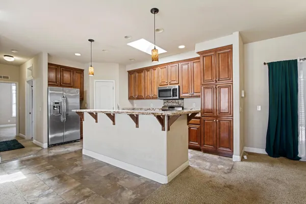 a view of kitchen with stainless steel appliances kitchen island granite countertop a refrigerator a stove a sink and a oven