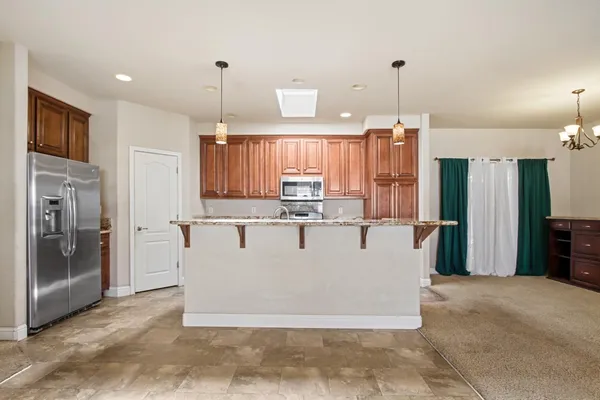 a view of a kitchen with stainless steel appliances granite countertop a refrigerator a oven and a sink with granite countertops