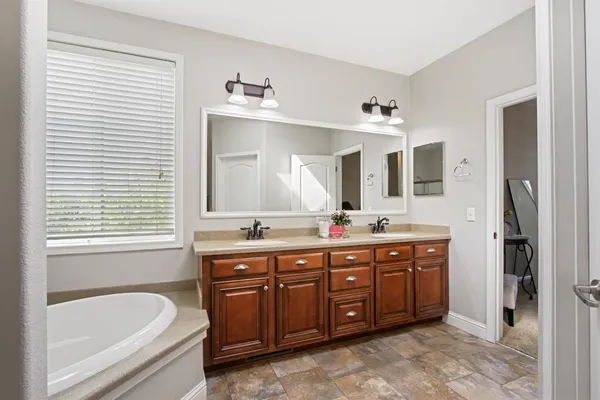 a spacious bathroom with a tub sink and mirror