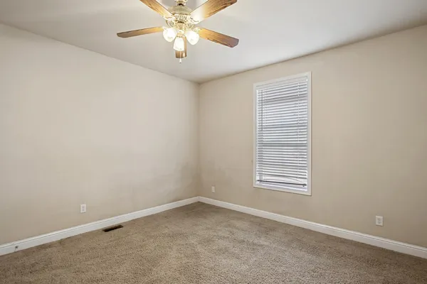 an empty room with windows and chandelier fan