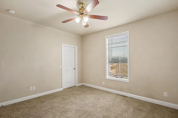an empty room with windows and fan