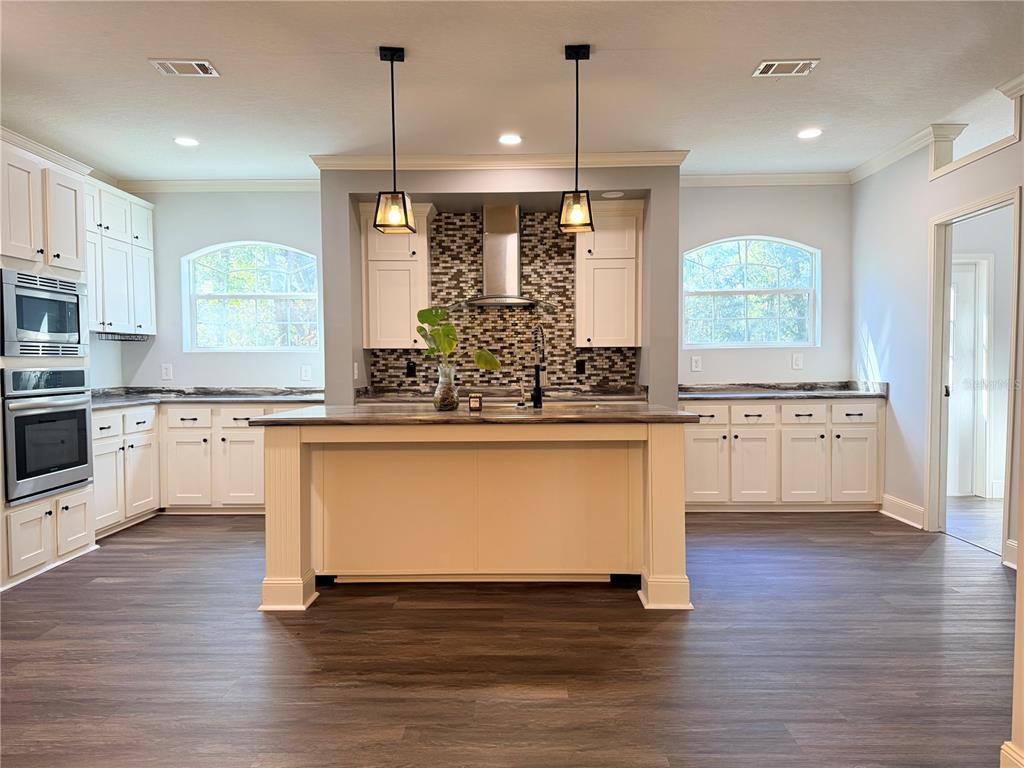 4440 Southwest 63rd Boulevard Gainesville, FL 32608 - Photo 15 of 49 a large kitchen with stainless steel appliances granite countertop a stove a sink and a wooden floor
