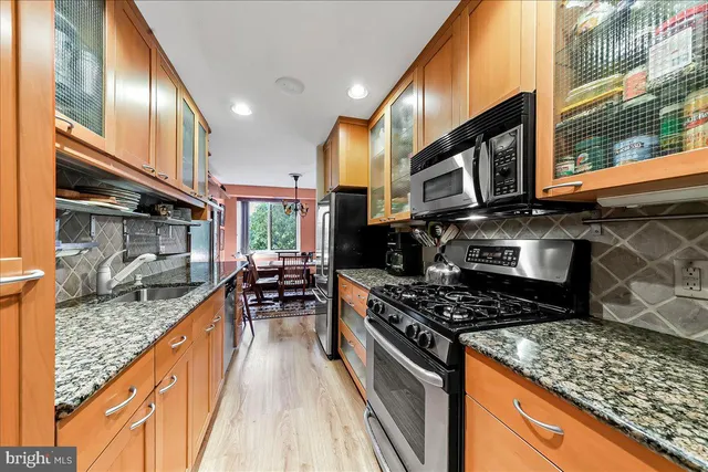 a kitchen with stainless steel appliances granite countertop a stove top oven a sink dishwasher and cabinets with wooden floor