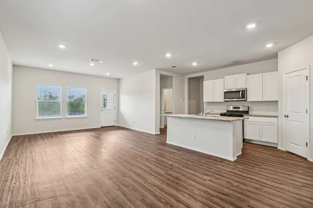 a view of kitchen with granite countertop stainless steel appliances counter space and wooden floor