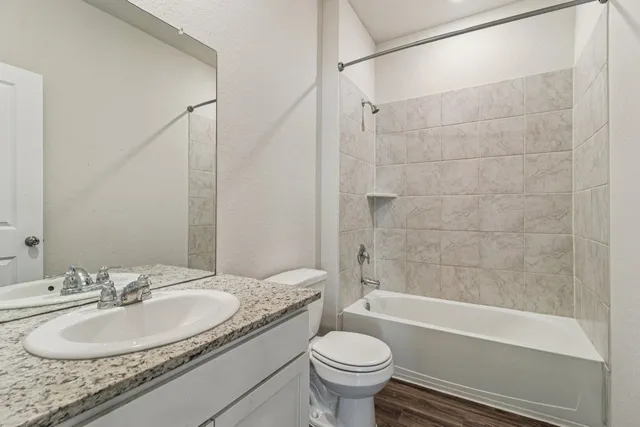 a bathroom with a granite countertop sink toilet mirror and bathtub