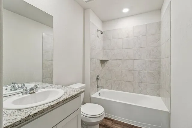 a bathroom with a granite countertop toilet a sink and a bathtub