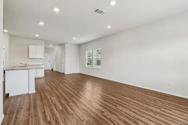 a view of kitchen and empty room with wooden floor