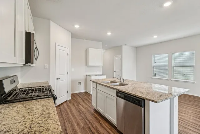 a kitchen with granite countertop a sink stove and cabinets