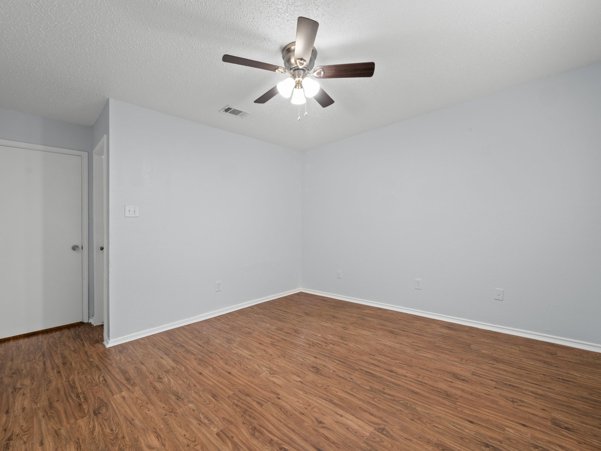 1816 Rawhide Loop, Unit 1822 Round Rock, TX 78681 - Photo 9 of 17 Empty room with wood finished floors, a ceiling fan, and a textured ceiling