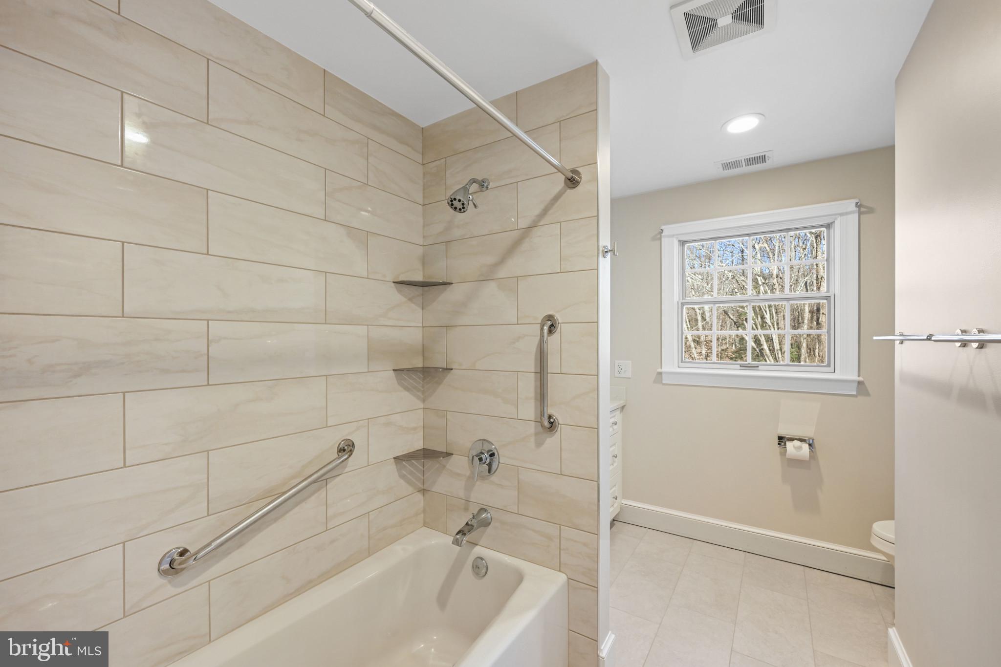 16966 Teagues Point Road Hughesville, MD 20637 - Photo 17 of 72 a bathroom with a bathtub a shower and a window