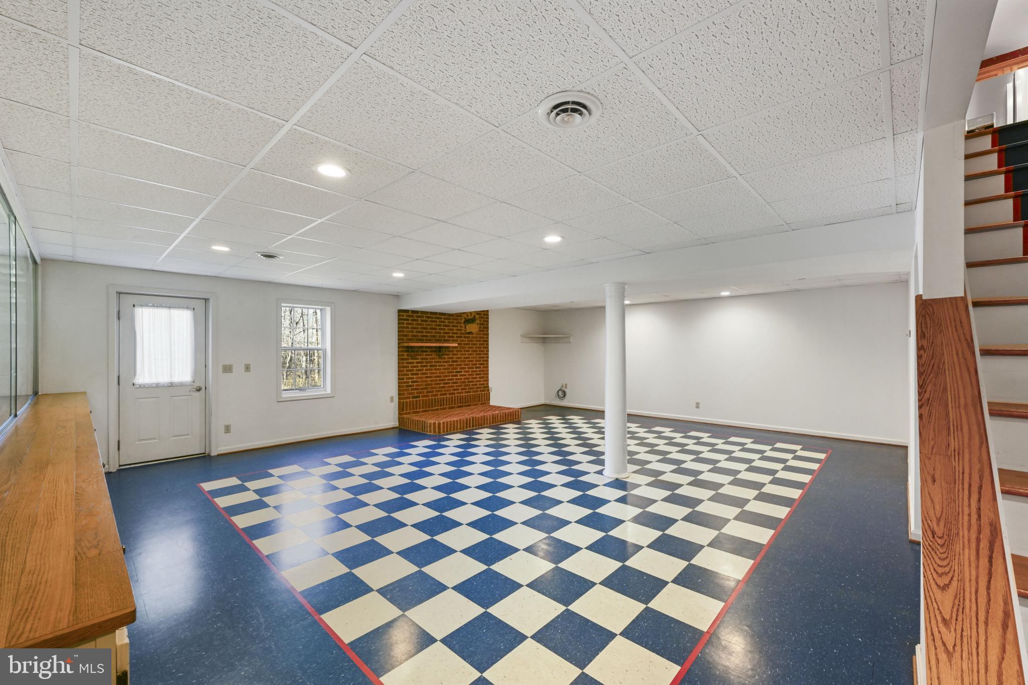 16966 Teagues Point Road Hughesville, MD 20637 - Photo 33 of 72 a living room with a black white checkered floor with a gaming machine and wooden floor